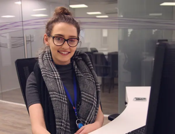 Person looking at the camera, sat at a desk.