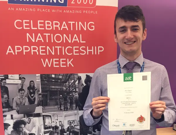 Alex stood showing his AAT certificate