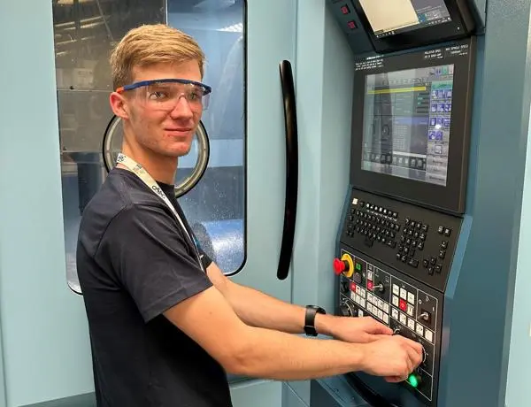 Alfie, wearing safety goggles, stood in front of an engineering machine