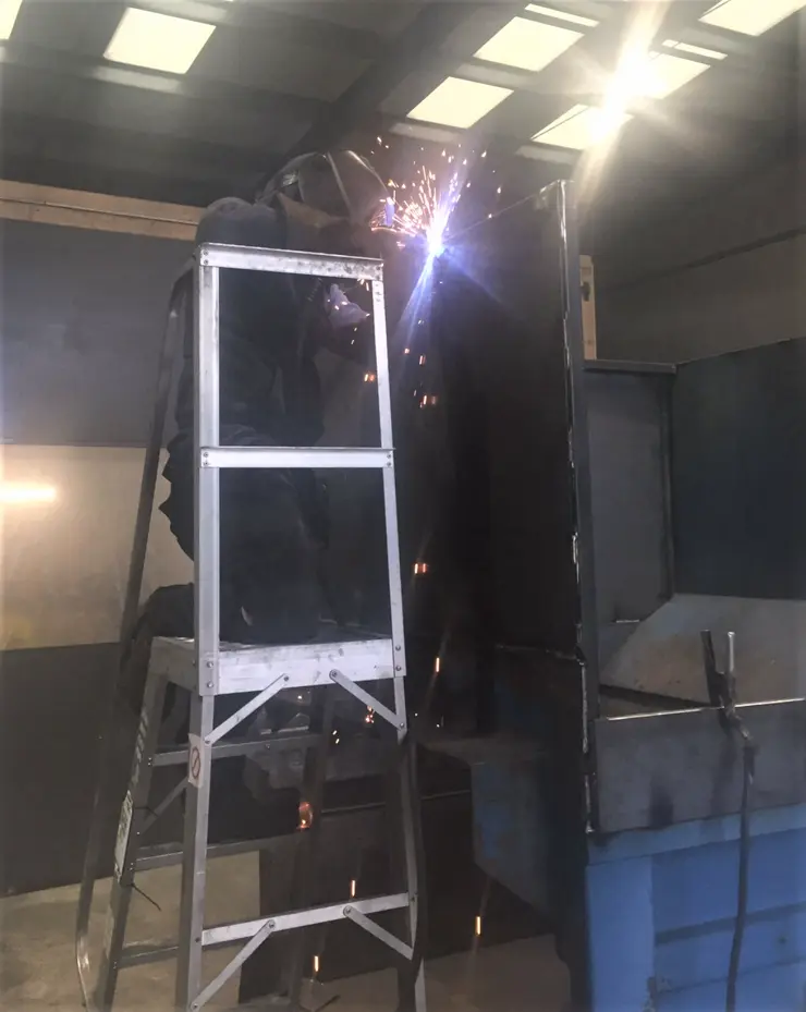 Person, stood on a laddered platform and, welding