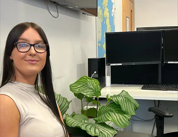 Holly, sat at a desk, looking at the camera