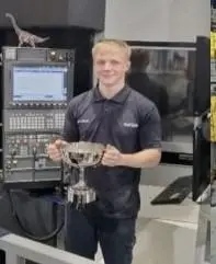 Luke, stood in an engineering environment, holding a trophy