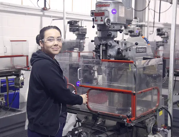 Person, looking at the camera, stood in front of an engineering machine
