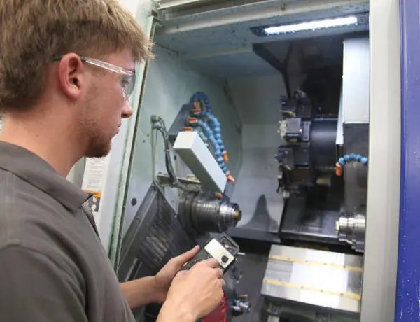 Charlie, wearing safety goggles. stood in front of an engineering machine