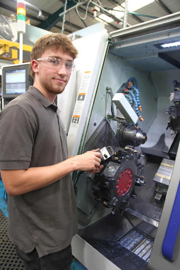Charlie, wearing safety goggles, stood in front of an engineering machine