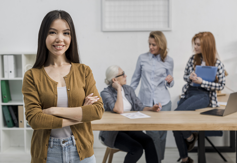Young person looking at the camera while three other people have a discussion in the background